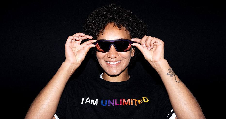 Danieca Coffey smiling and showing off goodr sunglasses in black I Am Unlimited t-shirt