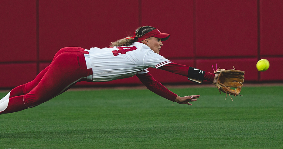 Jayda Coleman flies in mid air as she dives for a ball in the outfield while playing for Oklahoma.