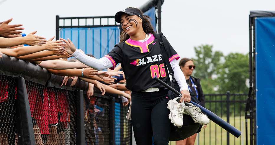 McKenzie Clark in black and pink Carolina Blaze jersey high fives fans by the fence